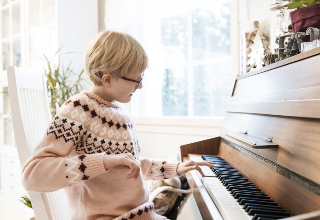 Hillamaija vaaleissa polkamittaisissa hiuksissaan ja punaisissa silmälaseissaan soittamassa pianoa.